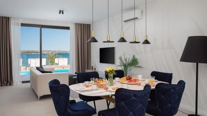 A dining area with a table set for breakfast, a view of the sea, and a modern interior design. - Stunning home in Tkon (Tkon)
