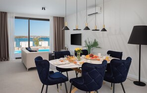 Ein Essbereich mit einem für das Frühstück gedeckten Tisch, Blick auf das Meer und modernem Interieur.