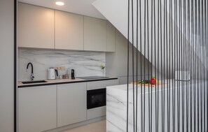 Eine moderne Küche mit Marmorfliesenspiegel, einem eingebauten Ofen und einer schwarzen Arbeitsplatte.