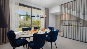 A modern dining area with a table set for breakfast, large windows, and a view of the outdoors. - Gorgeous home in Tkon (Tkon)