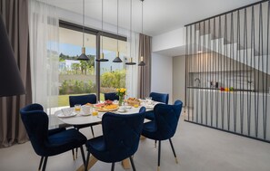 A modern dining area with a table set for breakfast, large windows, and a view of the outdoors. - Gorgeous home in Tkon (Tkon)