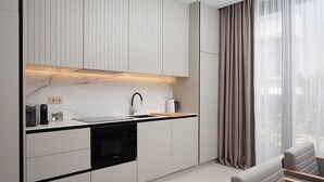 A modern kitchen with a built-in oven, a sink, and a coffee maker. - Luxurious home in Tkon (Tkon)
