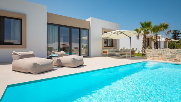 A modern poolside area with a clear blue pool, outdoor seating, and a stone wall. - Luxurious home in Tkon (Tkon)