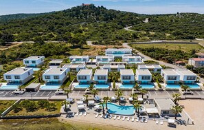 Ein Resort mit modernen Gebäuden, einem Swimmingpool und Blick auf einen Hügel.