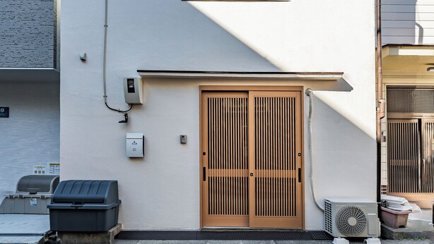 A two-story building with a white exterior, a wooden door, and a small window. - house tabiji nishikujyo (Nishikujo, Konohana Ward)