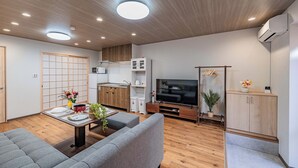 A modern living room with a sofa, TV, and kitchen area. - house tabiji nishikujyo (Nishikujo, Konohana Ward)