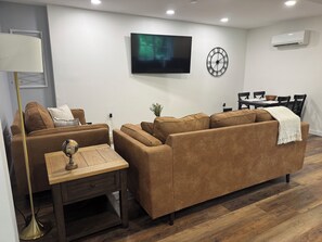 Ein modernes Wohnzimmer mit braunem Sofa, Couchtisch aus Holz, Globus und Wandfernseher.
