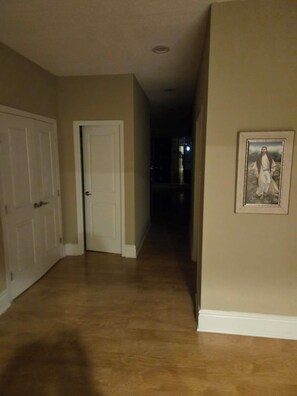 A hallway with wooden flooring, white doors, and a framed picture on the wall.