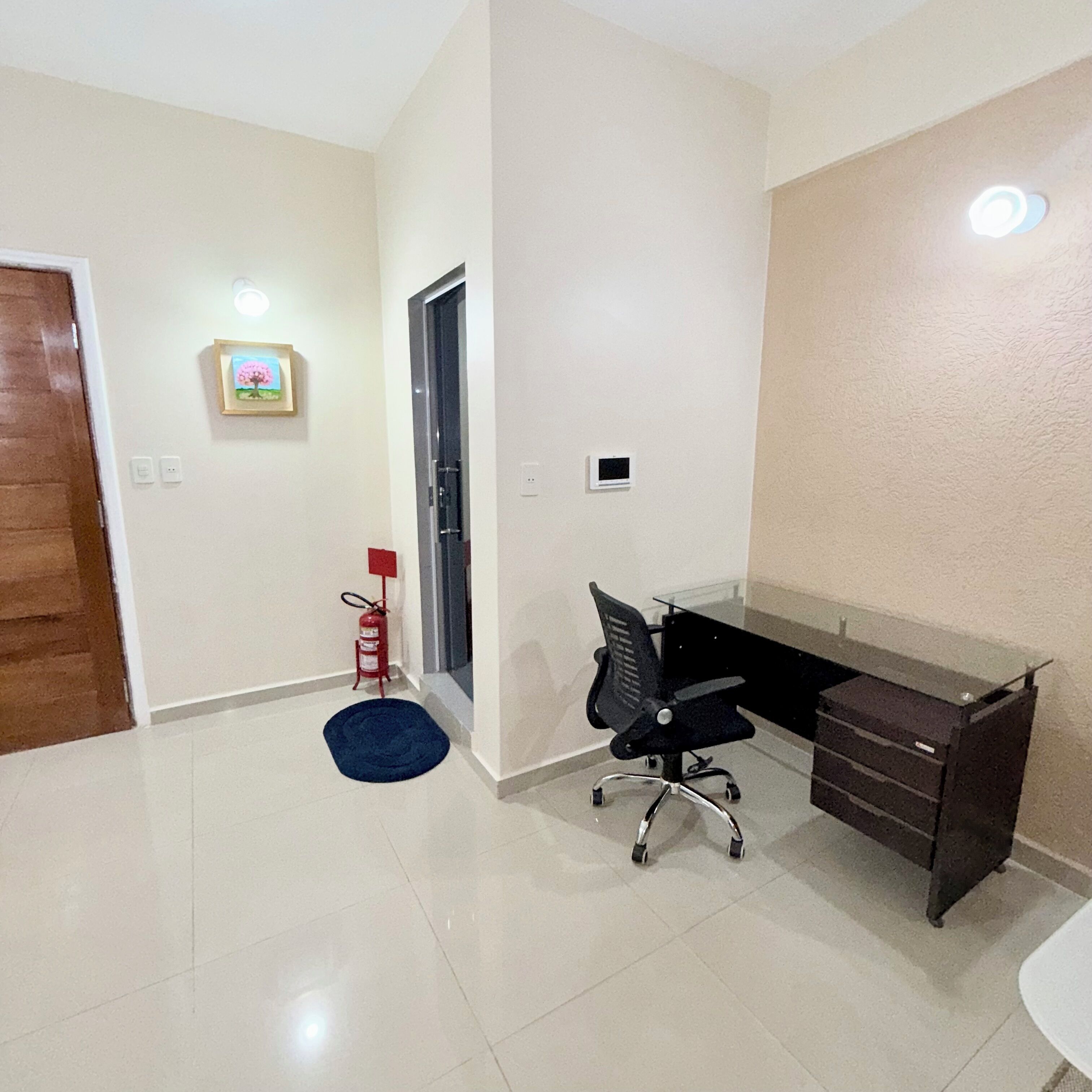 Una habitación con escritorio, silla y extintor.