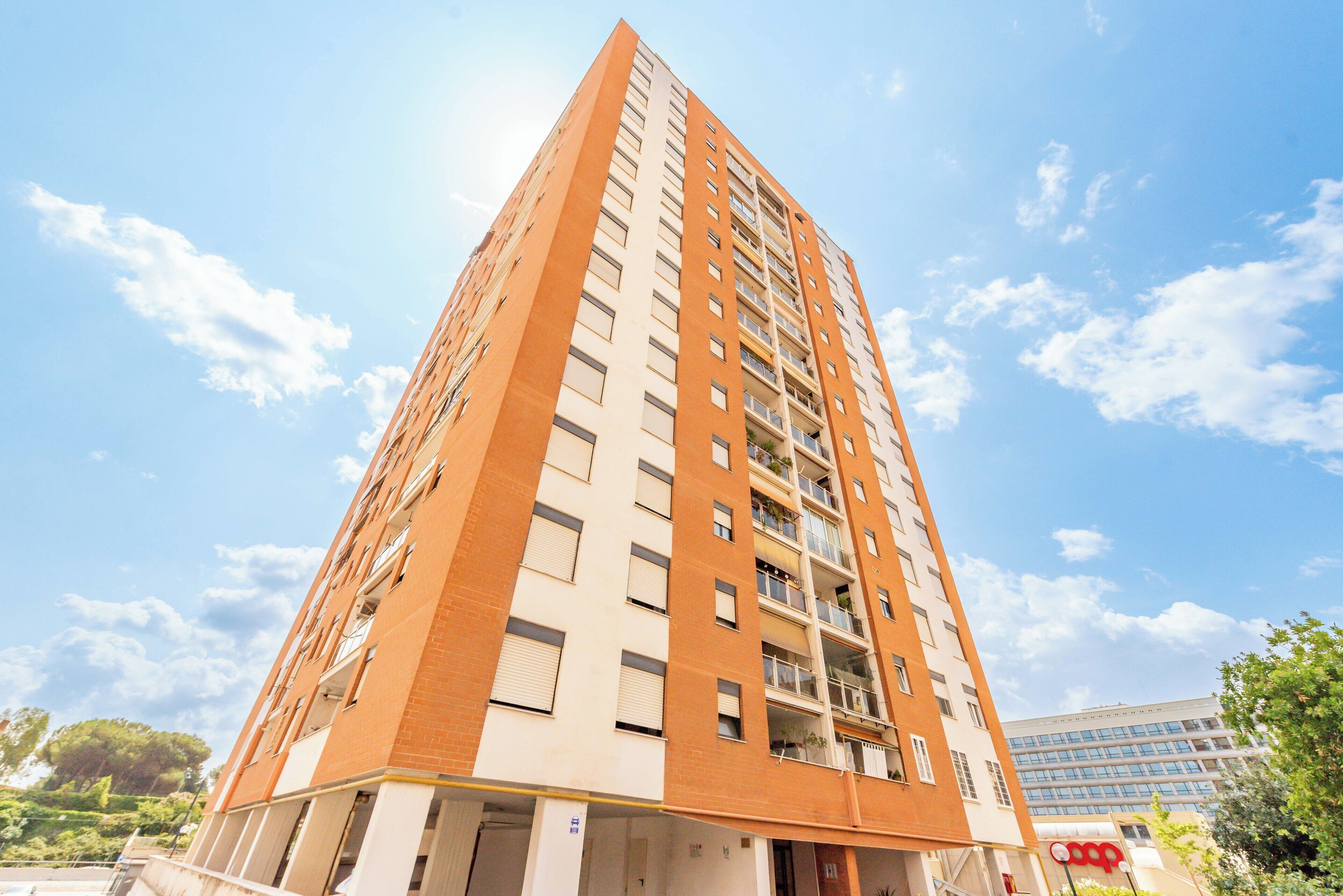 A high-rise building with multiple floors, balconies, and a clear sky.