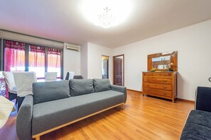 A living room with a grey sofa, wooden dresser, and a mirror. - Schiaccianoci Apartment (Rome)