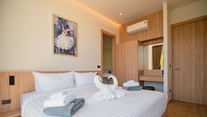 A hotel room with a large bed, a painting on the wall, a mirror, and an air conditioning unit. - Villa Kauri 3BR at Aileen Naithon (Sa Khu)