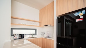 A modern kitchen with a black refrigerator, wooden cabinets, a marble countertop, and a coffee machine. - Villa Kauri 3BR at Aileen Naithon (Sa Khu)
