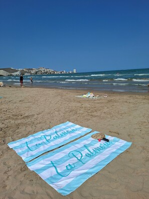 A beach with a towel laid out on the sand, a hat, and a pair of sunglasses. - La Palmera - Amazing beachfront terrace (Cullera)
