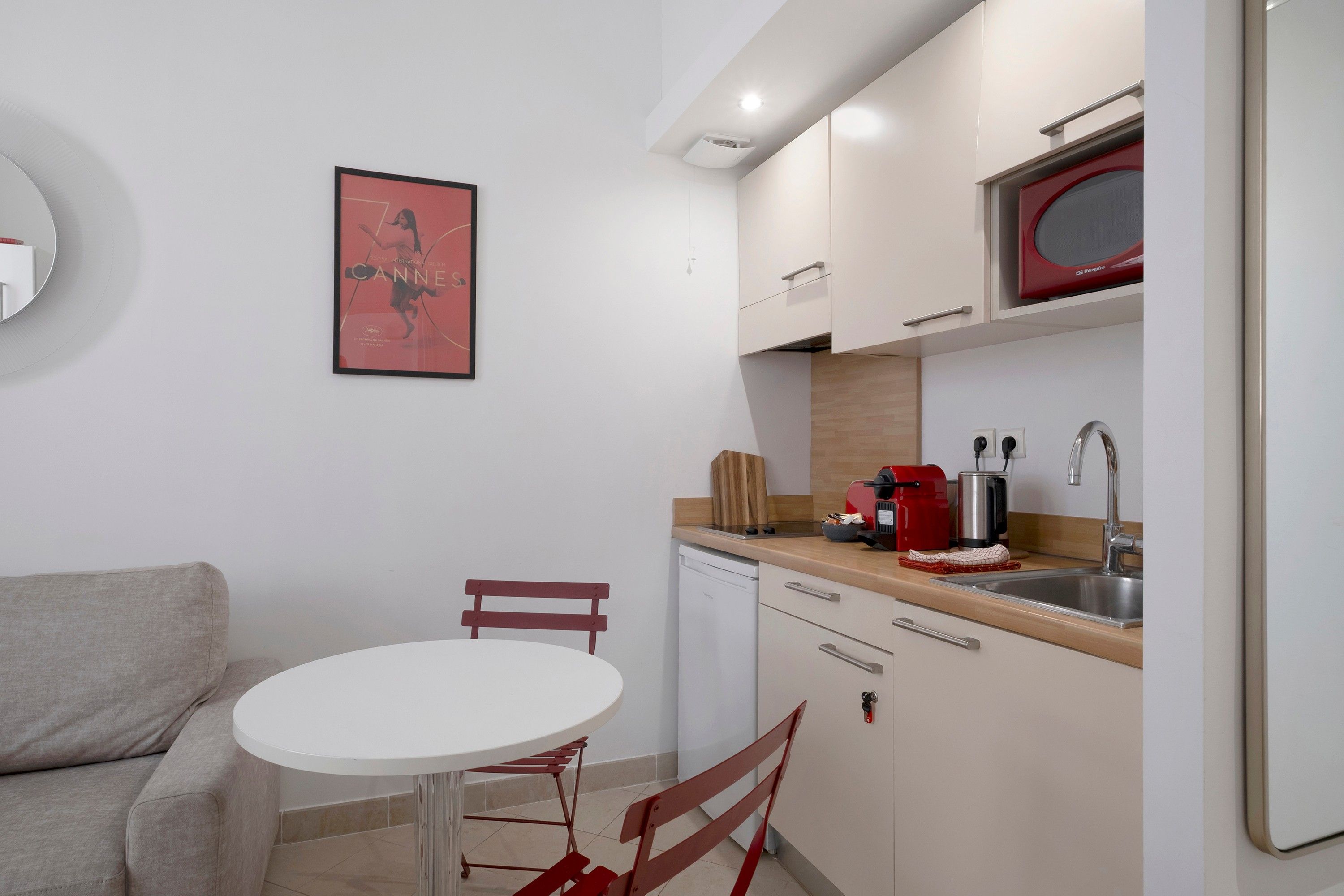 A compact kitchen with a white countertop, a red toaster, and a sink.