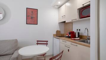 A compact kitchen with a white countertop, a red toaster, and a sink.