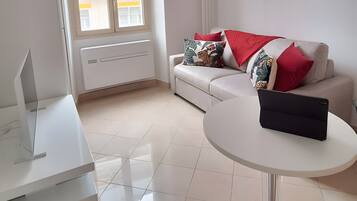 A modern living room with a sofa, a round coffee table, and a white cabinet.