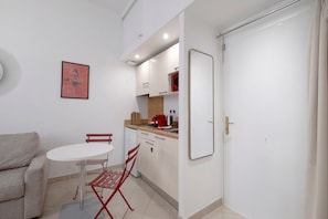 Ett kompakt bostadsutrymme med ett litet kök, en matplats med bord och stolar samt en separat sittgrupp med en soffa.