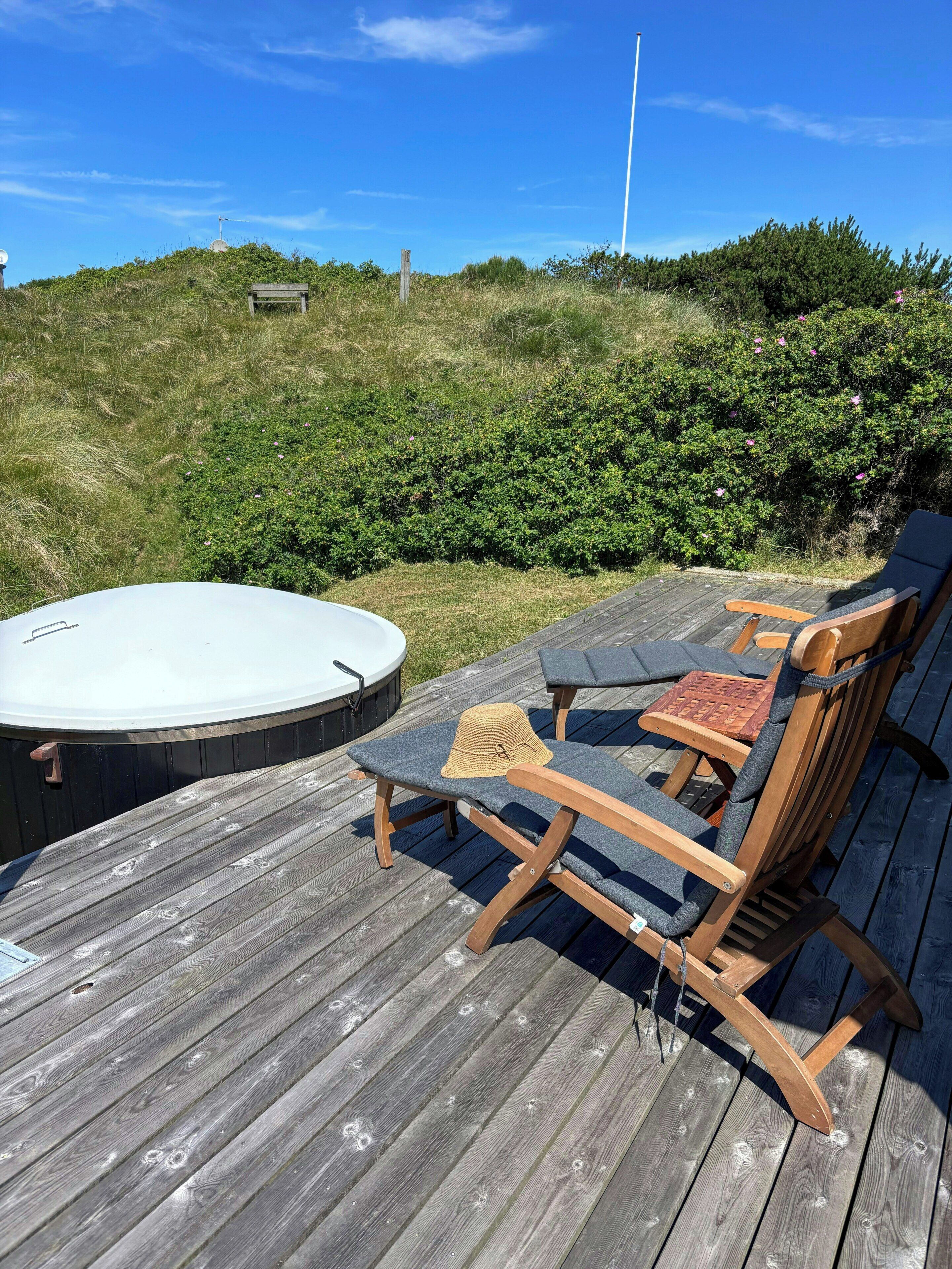 A wooden deck with lounge chairs and a hot tub.