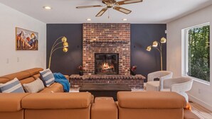 Ein modernes Wohnzimmer mit Kamin aus Ziegelsteinen, einer Ledersofa und einem Deckenventilator.