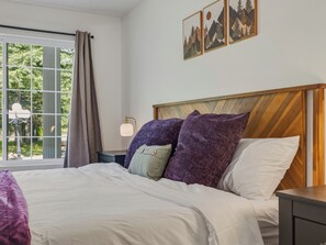 A bedroom with a large bed, a nightstand, a lamp, and a window with curtains. - Riverfront Resort w/ Spa~Firepit~Hammock~Theater~Games~Sleeps 20~Amazing Views (Gold Bar)
