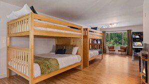 Ein Schlafraum mit Etagenbett, Flachbildfernseher, Kamin und Blick ins Freie.