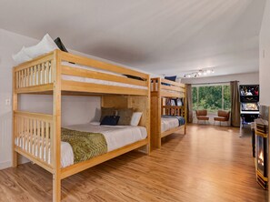 Ein Schlafraum mit Etagenbett, Flachbildfernseher, Kamin und Blick ins Freie.