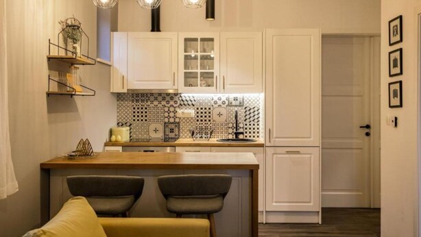 A modern kitchen with white cabinets, a patterned backsplash, pendant lighting, and a bar area with stools. - Luxury Villa Lara With Heated Pool, Hot-tub and Sauna - Six Bedroom Villa With Pool (Zmijavci)