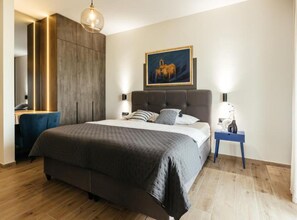Ein modernes Schlafzimmer mit einem großen Bett, einem Schreibtisch und einem Gemälde an der Wand.