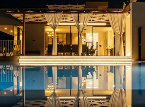 Ein modernes Hotel mit Pool, einem Innenbereich zum Essen und einem gut beleuchteten Eingang.