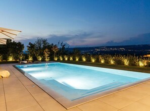 A swimming pool with a view of a cityscape at dusk.
