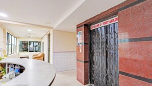 Zona de recepción con un mostrador curvo, una estatua y una puerta con un cartel que dice 'THANK U. VISIT AGAIN'.