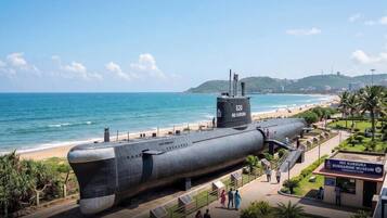 A submarine on display near a beach with a museum sign.