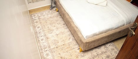 A bedroom with a bed, a rug, and a door.