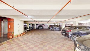 Un parking à plusieurs niveaux, doté d’un sol carrelé et abritant divers véhicules, notamment des voitures et des motos.