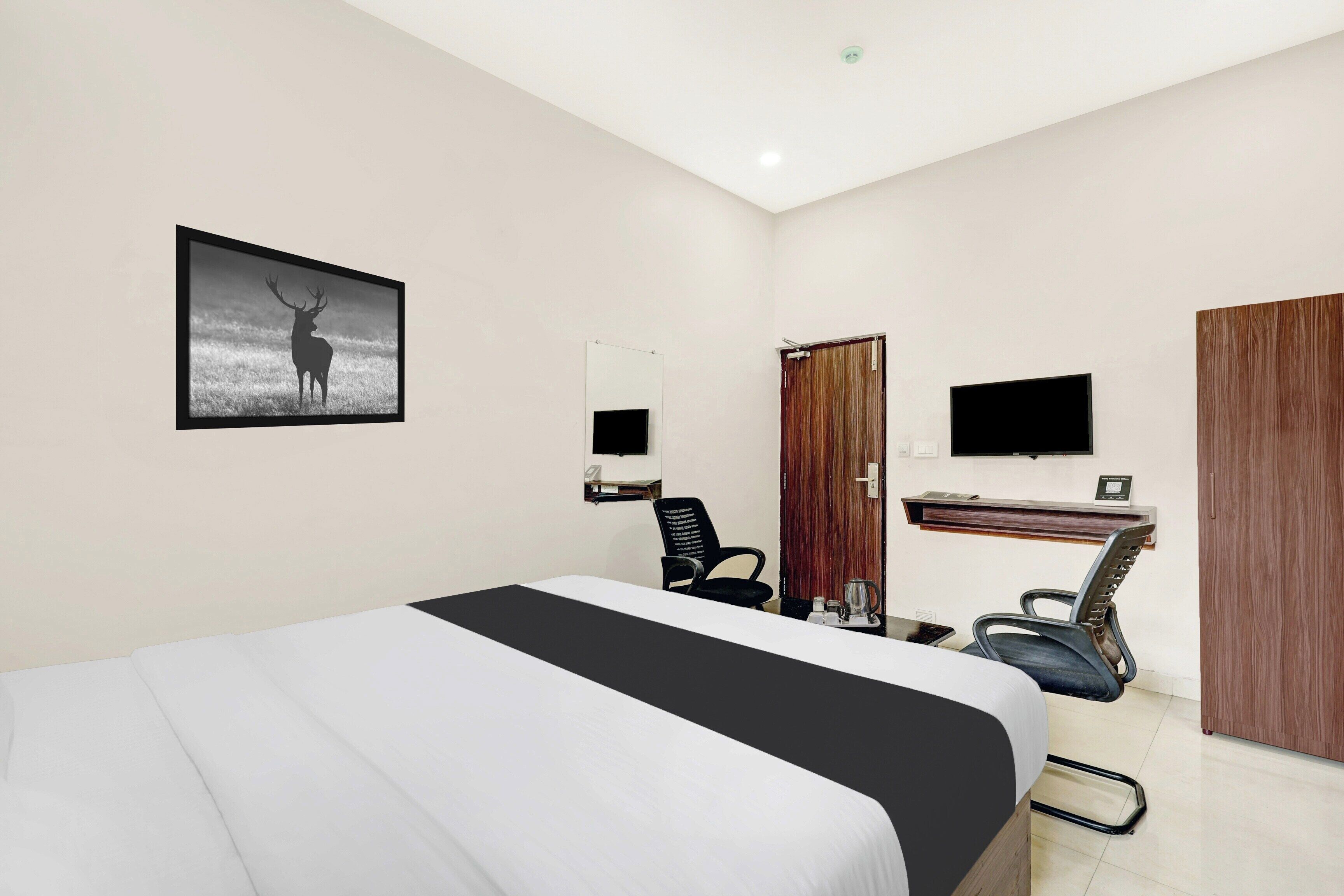 Ein Hotelzimmer mit einem Bett, einem Schreibtisch, einem Sessel, einem Fernseher und einer Tür.