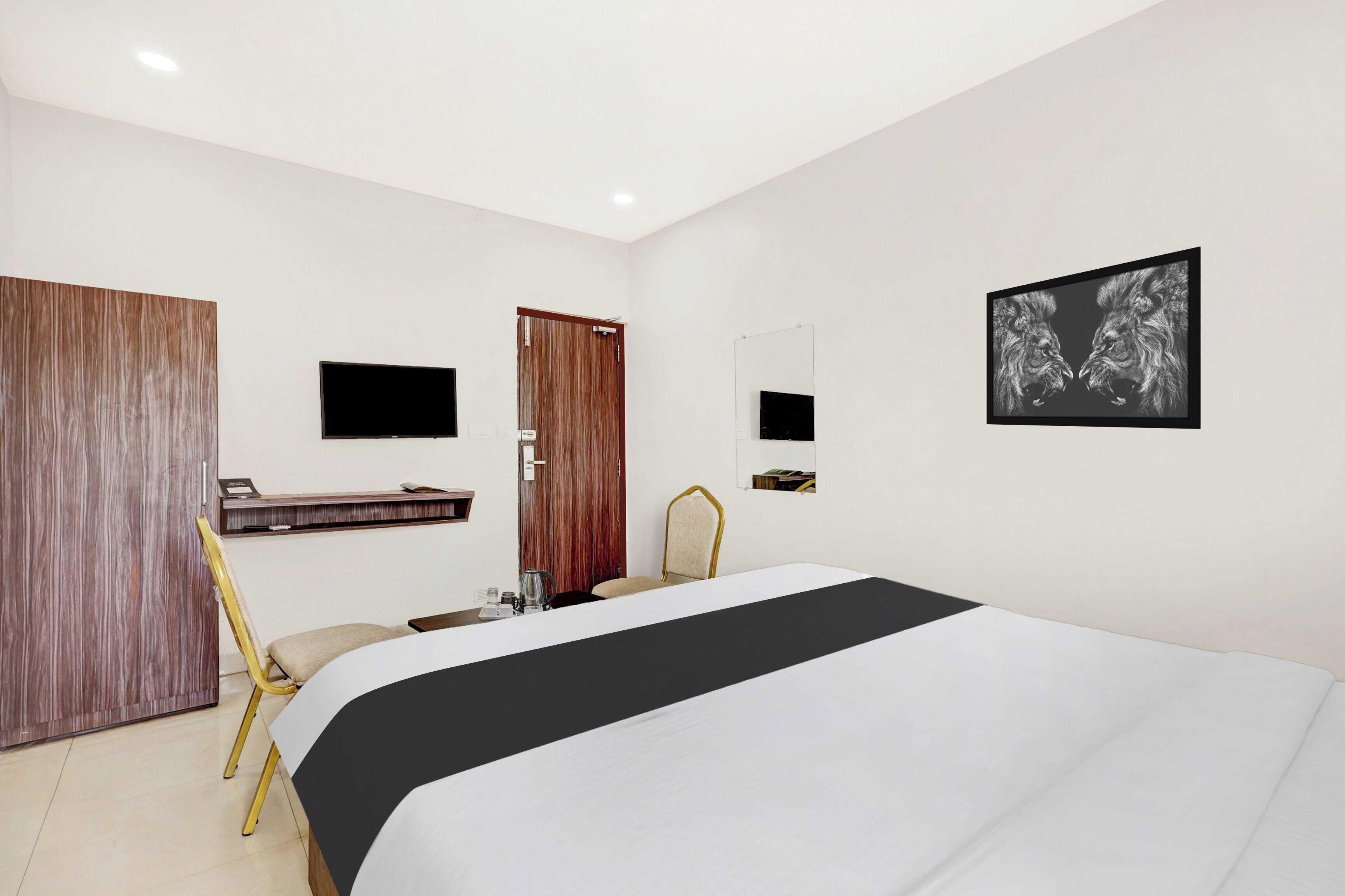 Habitación de hotel con cama, escritorio, silla, televisor y un cuadro en la pared.