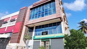 Un immeuble à plusieurs étages doté d’une architecture moderne, caractérisé par de grandes fenêtres en verre et une façade aux couleurs variées, allant du rouge au brun.