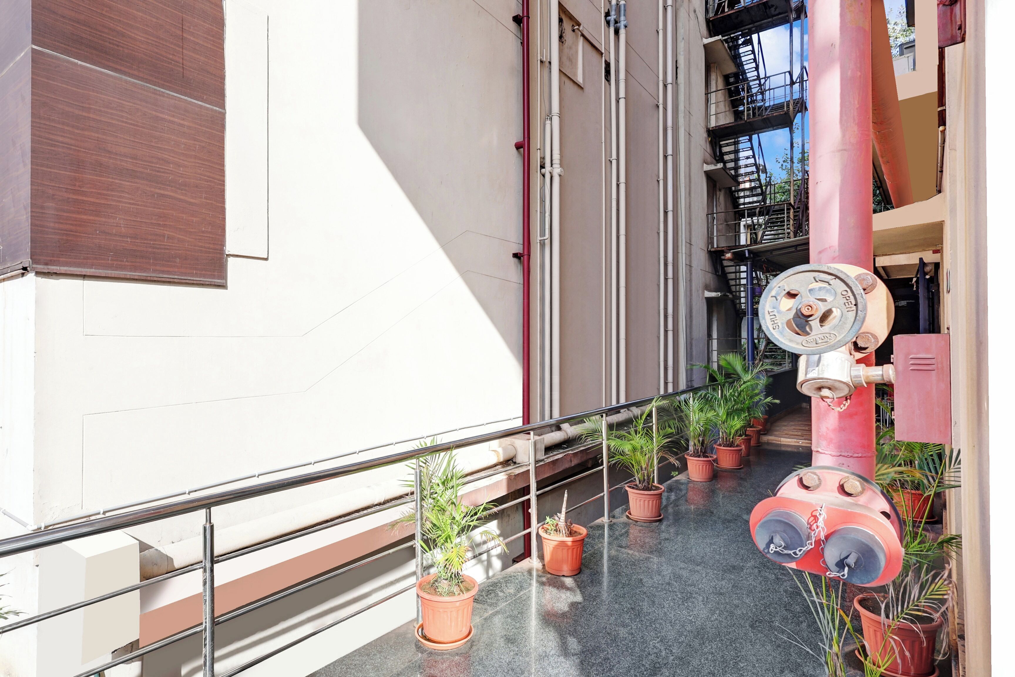 Ein Korridor mit Metallgeländer, Blumentöpfen und einem Brandschutzgerät.