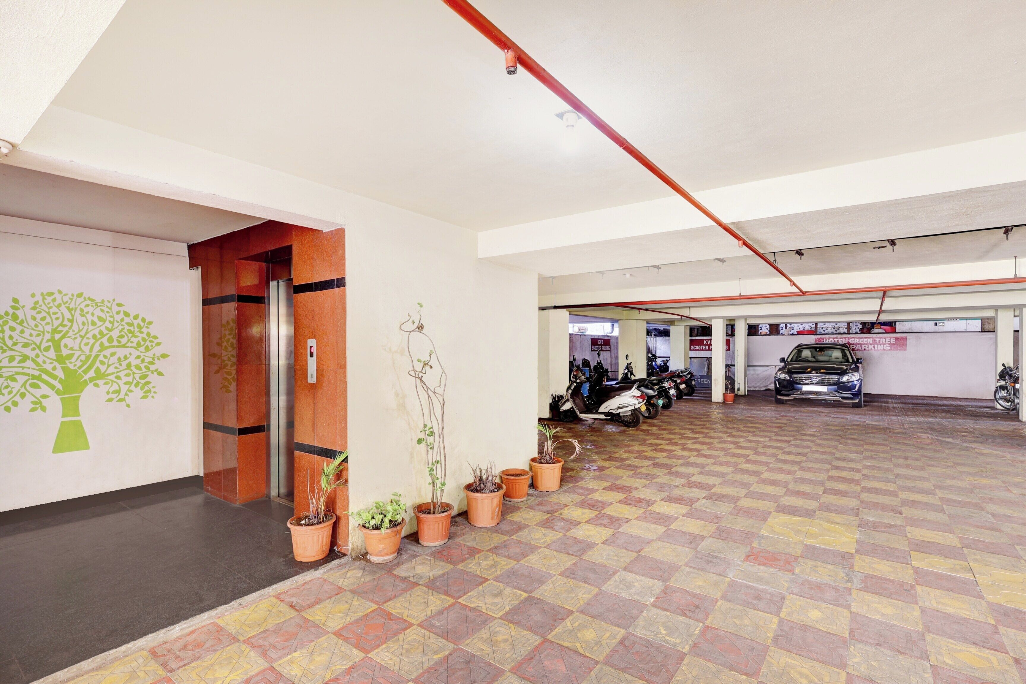 Un espace de stationnement doté d’un sol carrelé, de plantes en pot et d’un scooter.