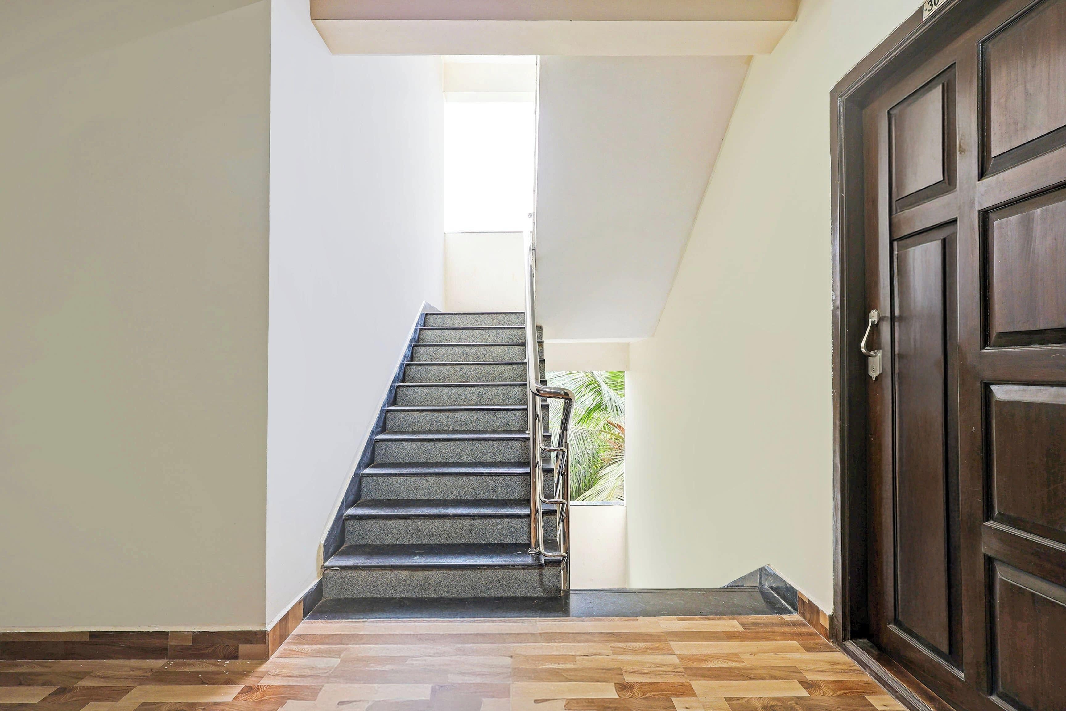 A staircase leading to an upper floor, a wooden door, and a plant visible through a window.