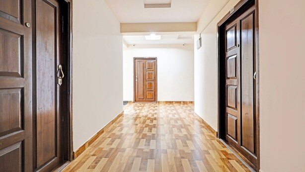 A hallway with wooden doors and a herringbone-patterned floor. - Super Collection O Beach Road Near GITAM (Visakhapatnam)
