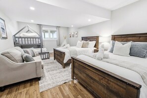 A bedroom with a bunk bed, a sofa, a bedside table, and a large bed with multiple pillows.