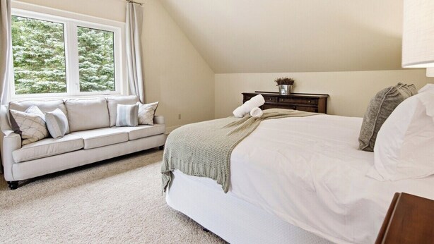 Une chambre à coucher avec un lit, un canapé, une table de chevet et une fenêtre avec des rideaux.