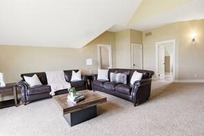 A living room with two dark brown leather sofas, a wooden coffee table, and a carpeted floor. - Greystone Lavender Farm-Hot Tub|Pool Table|KoiPond (Meaford)