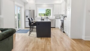 Une cuisine moderne dotée d’un îlot central, de meubles blancs et offrant une vue par une fenêtre.