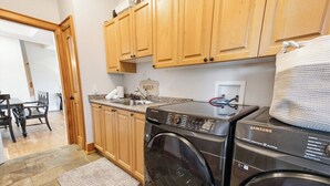 Une cuisine avec des meubles en bois, un lave-linge et un plan de travail en granit.