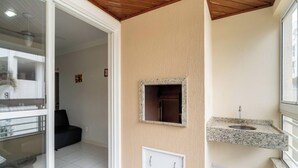 A modern bathroom with a granite countertop, a small sink, and a mirror. - Apartment With Balcony and Barbecue Cac0109 (Florianópolis)