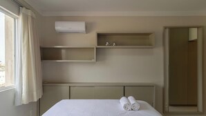 A hotel room with a bed, a wall-mounted air conditioner, and a large mirror. - Apart w/ Gourmet Area 240m From the Beach Cac0301 (Florianópolis)
