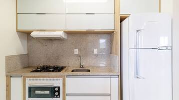 A compact kitchen with a built-in oven, a gas stove, a sink, and a refrigerator.